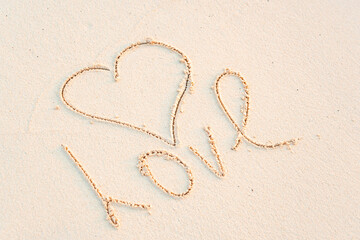 handwritten inscription heart and the word Love on the sand, the concept of travel and greetings for Valentine's Day