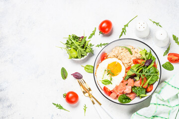 Savory breakfast. Oatmeal porrige with salted salmon, egg and fresh salad. Healthy food, balanced nutrition. Top view on white table.