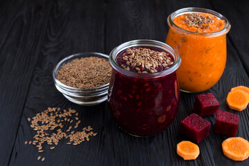 Closeup on vegetable smoothies or puree with flax seeds in the glass jars on the black surface