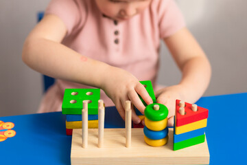 
Children's wooden toy. The child collects the sorter. Educational logic toys for children. Baby hands close up. Montessori games for child development