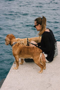 Young female with her cocker spaniels near sea