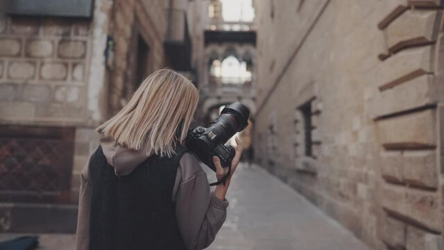 tourist woman wearing mask with dslr photo camera walking through old town narrow streets, Barcelona, Spain. She takes photos. covid tourism concept with coronavirus. Prores 10 bit color space