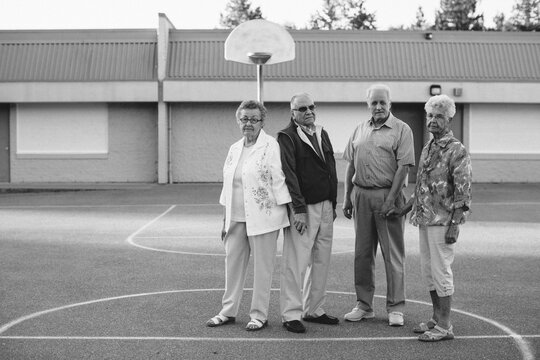 Funny portrait of grumpy caucasian seniors outside at schoolyard basketball courts