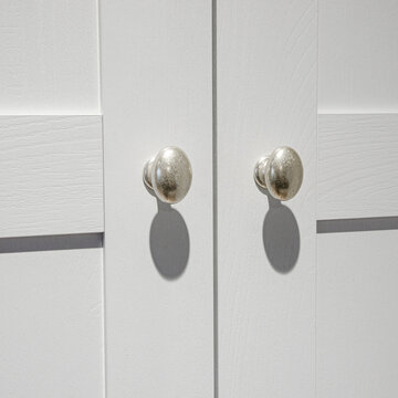 Furniture fittings. Metallic silver door handles with sharp shadows on the white facade
