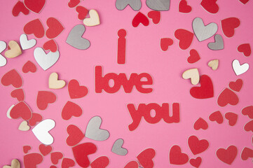 Word Love you and red hearts on pink background.  Birthday or Valentines day greeting card