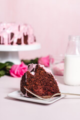 Homemade red velvet bundt cake with pink cream cheese frosting and valentine's day sprinkles on a pink background