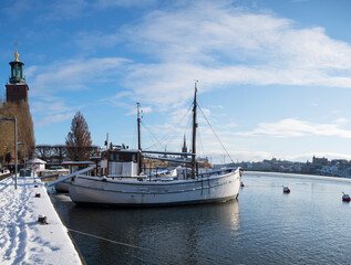 Harbour with old boats in a snowing, icy and cold winter day in Stockholm.