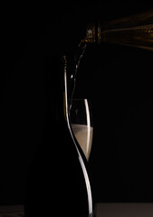 Red sparking wine on a wineglass and silhouette of black wine bottle.