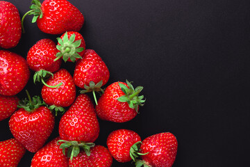 Red ripe strawberry background. Elegant dark background with red berries of strawberry on black concrete or stone. Copyspace
