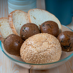 fresh delicious buns and slices of wheat bread on wooden kitchen table