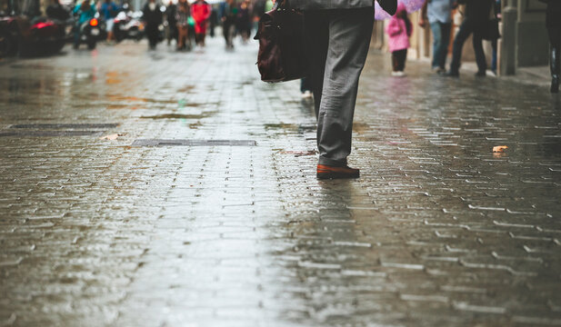 Businessman with briefcase walking down the street. Barcelona streets on rainy day.