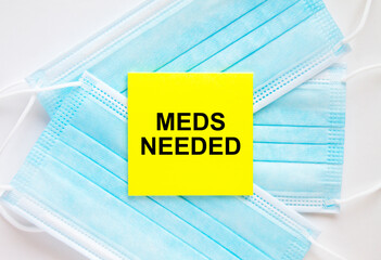 Yellow sticker with text Meds Needed lying on the masks