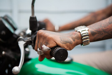 Tattooed hands on motorbike handlebars