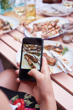Hand with smartphone taking food photo of grilled meat