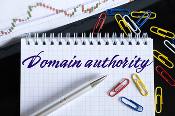 On the desktop are a forex chart, paper clips, a pen and a notebook in which it is written - Domain authority