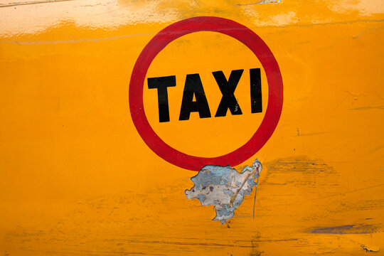 Taxi written in yellow colored bode of a car
