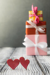 Two red hearts over defocused stack of gift boxes. Valentine’s day greeting