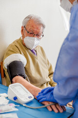 Nurse taking blood pressure of elderly man