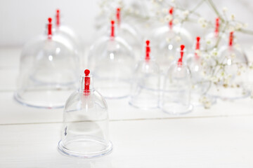 Jars for hijama on a white wooden background and white flowers. Bloodletting. Sunnah treatment. Islam.