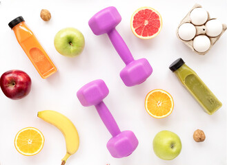 Top view of background with  fruits, smoothies and pink dumbbells for athletic performance and...