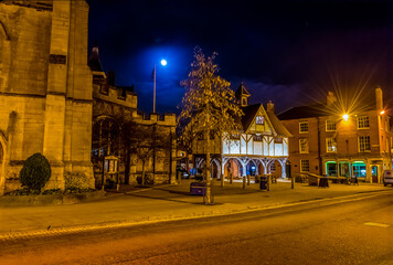 Fototapeta na wymiar The High Street and market square in Market Harborough, UK at night with a full moon in the background