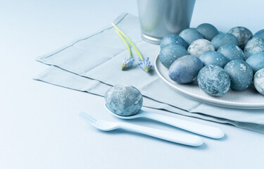 Stone Easter egg in spoon, flowers and plate with eggs in background.