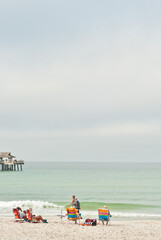 Obraz premium side view, very far distance of a family relaxing on colorful, beach chairs, on a tropical, isolated beach, shoreline 