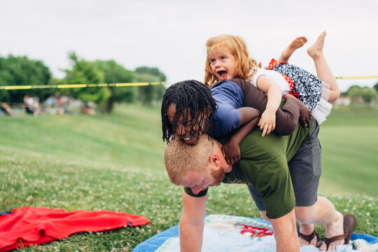 Father wrestling with daughters - Powered by Adobe