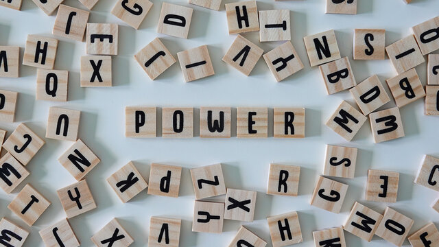 The word power spelled out in wooden craft letters surrounded by letters.