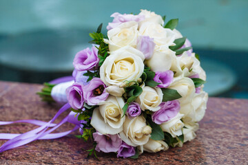 Beautiful wedding bouquet of natural flowers on a blurred background lies on granite