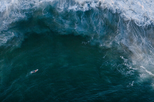 A lone surfer swims out to the impending surf