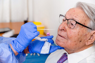 Nurse performing coronavirus test on elderly man