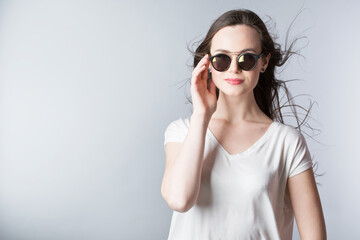 Portrait of a beautiful smiling woman in sunglasses with long straight hair in the wind.