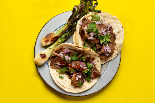 Grilled beef steak tacos on yellow background. Mexican food