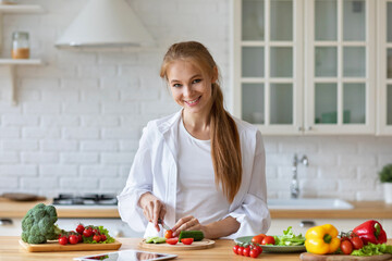Happy woman prepares vegetables in the kitchen.