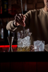 Fototapeta na wymiar Barman make alcohol cocktail at bar counter. Barman making Jungle Juice coctail in bar