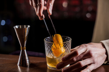 Orange peel in alcohol cocktail at bar counter. Barman making Jungle Juice coctail in bar