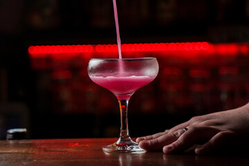 Classic Pink Lady cocktail closeup with flower and cherry on bar counter