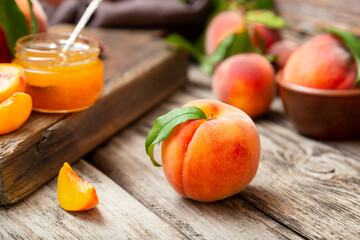 Whole peach fruit and wedges for making jam. Peach fruit with leaf. Ripe juicy orange peach fruit on wooden table. Peach harvest and jam on rustic kitchen closeup in dark mood