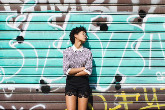 Relaxed woman leaning against rolling shutter