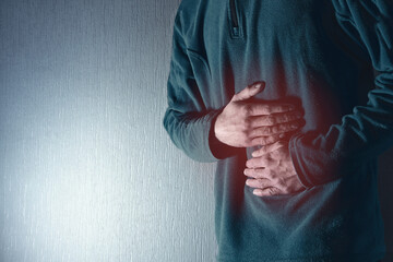 Man holds his belly with both hands. Stomach ache. Gastritis.  Blue grey background.