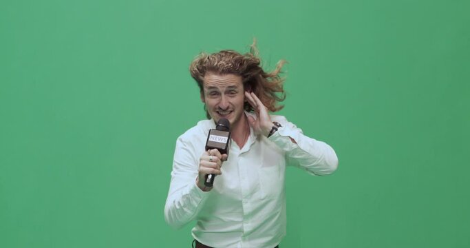 Studio, slow motion, green screen, young male reporter against the wind, London, UK