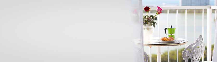 Breakfast with coffee on hotel's balcony, fresh croissants and slice of orange fruit. Long banner