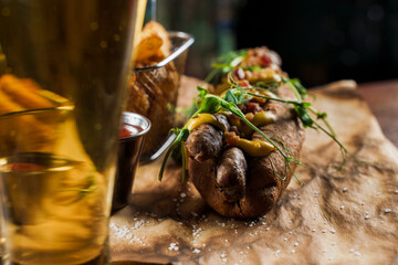 Barbecue grilled hot dog and beer with yellow mustard and ketchup on wooden background. Hot dog sandwich with potato fries and sauces.