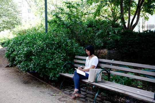 woman sitting in park, writing in notebook