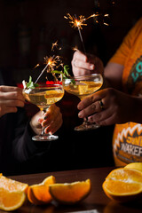 Celebrating new year eve 2022 with sparklers fireworks and drinking cocktails. Mint with orange slice in a cocktail glass filled with alcohol cocktails.