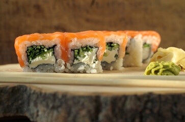 Sushi roll (Philadelphia) with salmon, smoked eel, avocado, cream cheese on wooden background. Sushi menu. Japanese food.