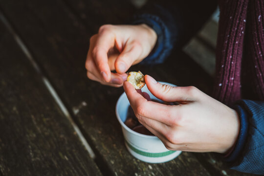 Male hands holding fresh roasted chestnut and planning to eat it. Seasonal outdoor street market food. Soft selective focus, copy space.
