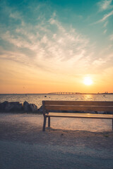 Fototapeta na wymiar Isolated public bench at sunrise. Re island bridge in the background. portrait format