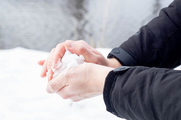 Caucasian hands forming a snowball out of the fresh snow during winter in Europe. Enjoying cold snowy weather after Beast from the East climate change.